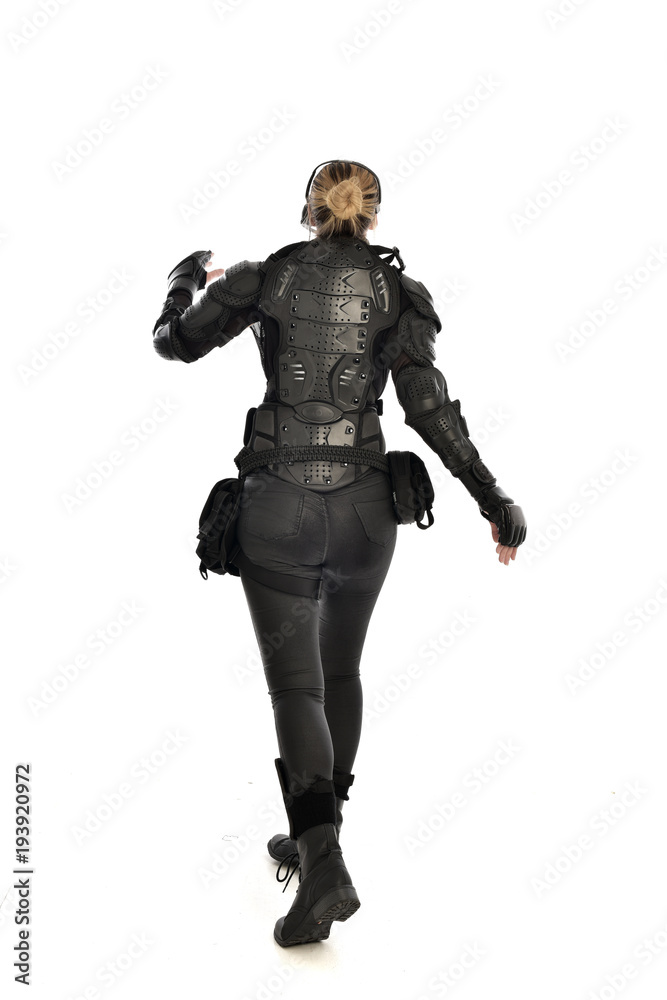 full length portrait of female  soldier wearing black  tactical armour  facing away from camera, isolated on white studio background.