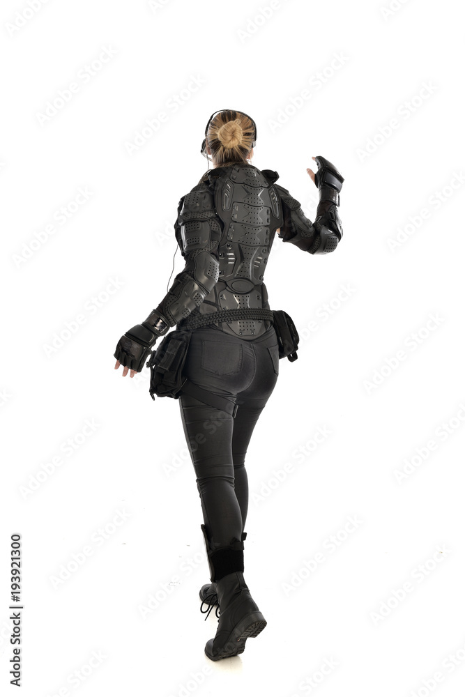 full length portrait of female soldier wearing black tactical armour facing away from camera, isolated on white studio background. full length portrait of female soldier wearing black tactical armour facing away from camera, isolated on white studio background.