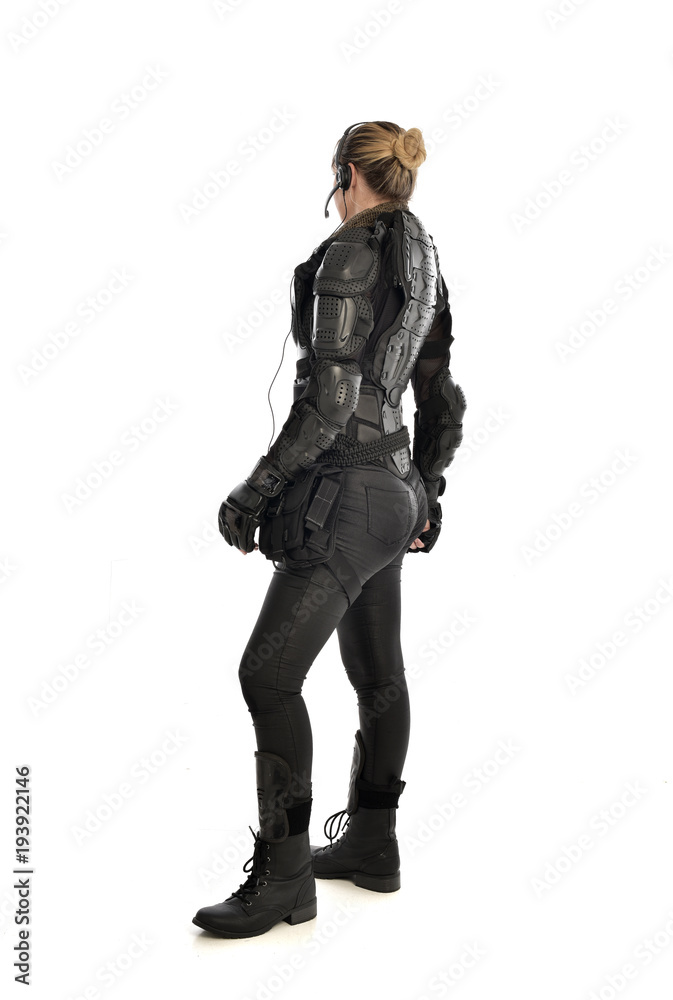 full length portrait of female soldier wearing black tactical armour facing away from camera, isolated on white studio background. full length portrait of female soldier wearing black tactical armour facing away from camera, isolated on white studio background.