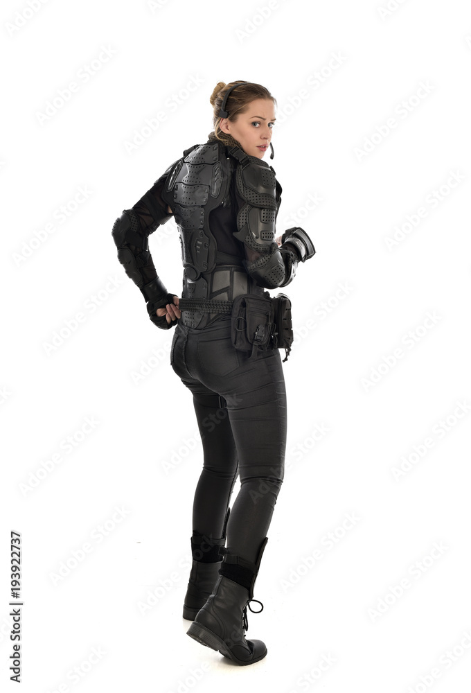 full length portrait of female soldier wearing black tactical armour facing away from camera, isolated on white studio background. full length portrait of female soldier wearing black tactical armour facing away from camera, isolated on white studio background.
