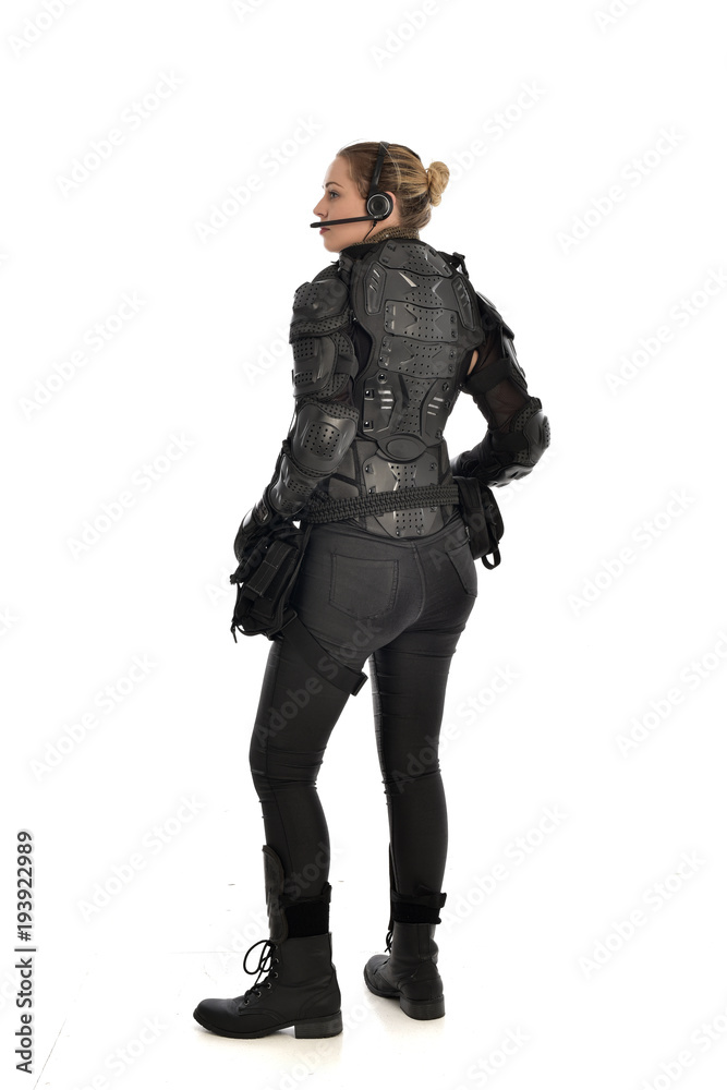 full length portrait of female  soldier wearing black  tactical armour  facing away from camera, isolated on white studio background.