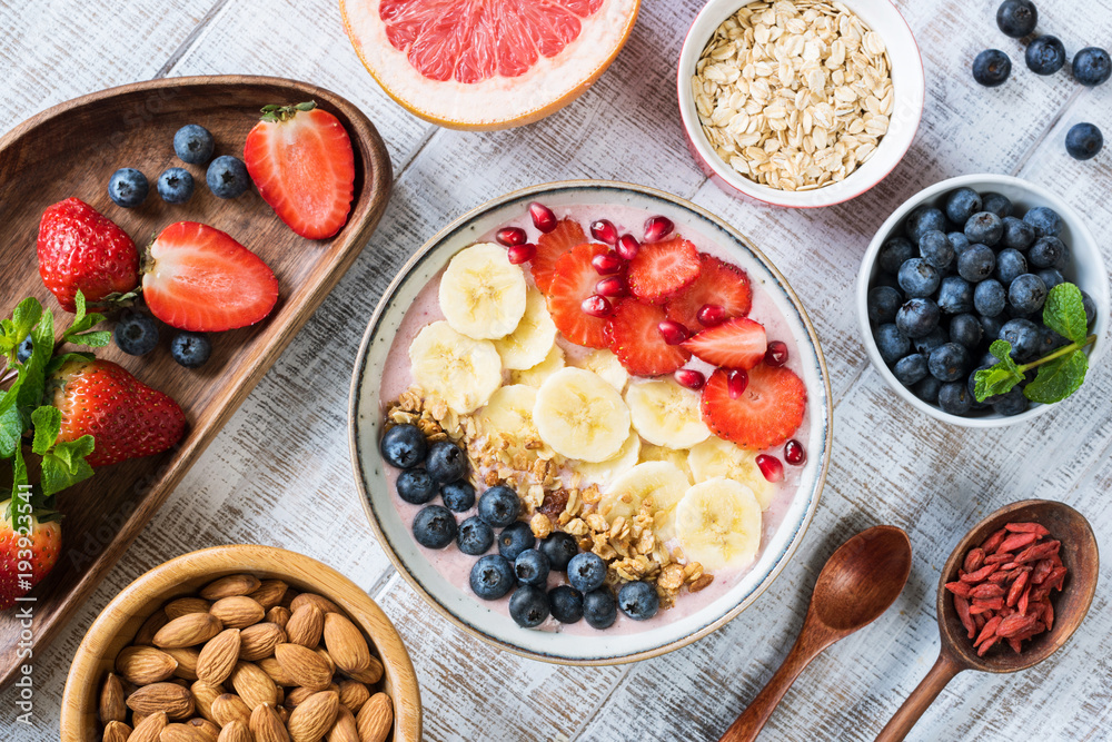 Smoothie bowl with banana slices, strawberry, blueberries, granola and pomegranate seeds. Top view. Healthy lifestyle, healthy eating, dieting, weight loss concept Smoothie bowl with banana slices, strawberry, blueberries, granola and pomegranate seeds. Top view. Healthy lifestyle, healthy eating, dieting, weight loss concept