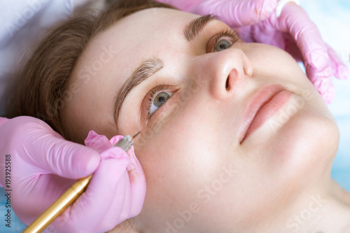 Permanent microblasting tattooing freckles to a woman in a beauty salon.