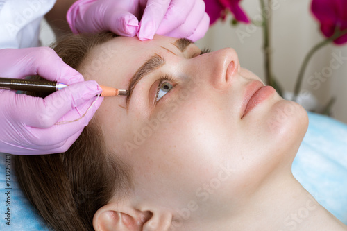 Permanent microblasting tattooing freckles to a woman in a beauty salon. photo