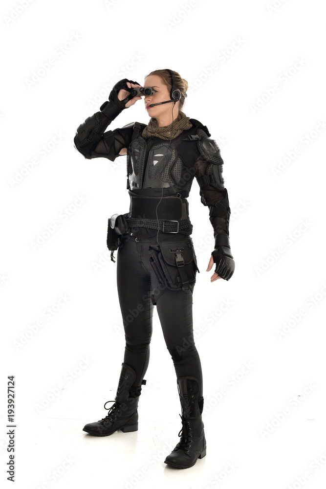full length portrait of female soldier wearing black tactical armour holding a pair of binoculars, isolated on white studio background. full length portrait of female soldier wearing black tactical armour holding a pair of binoculars, isolated on white studio background.
