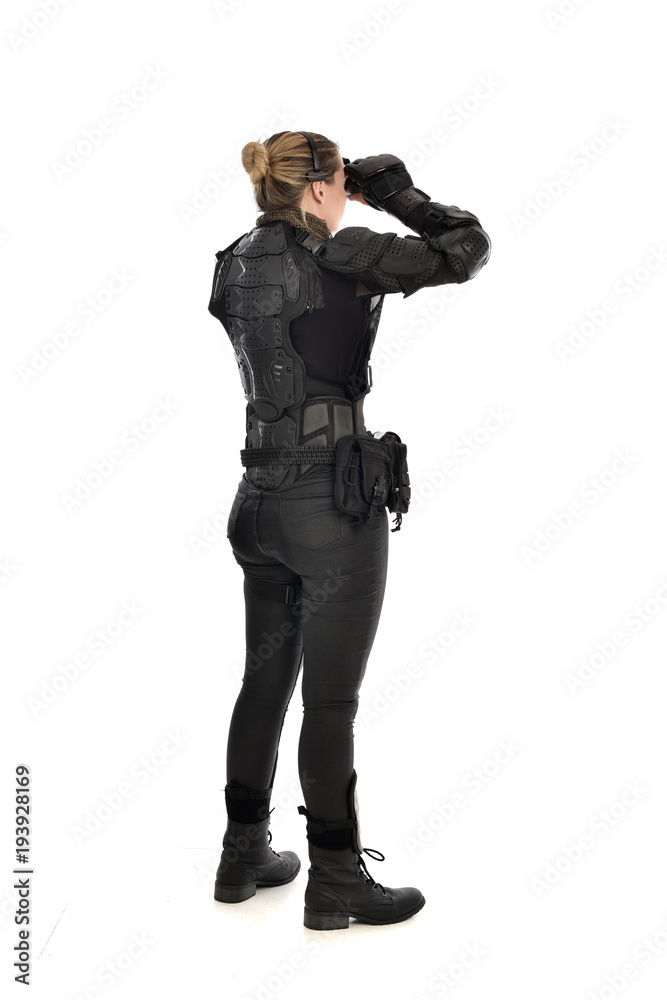 full length portrait of female soldier wearing black tactical armour holding a pair of binoculars, isolated on white studio background. full length portrait of female soldier wearing black tactical armour holding a pair of binoculars, isolated on white studio background.