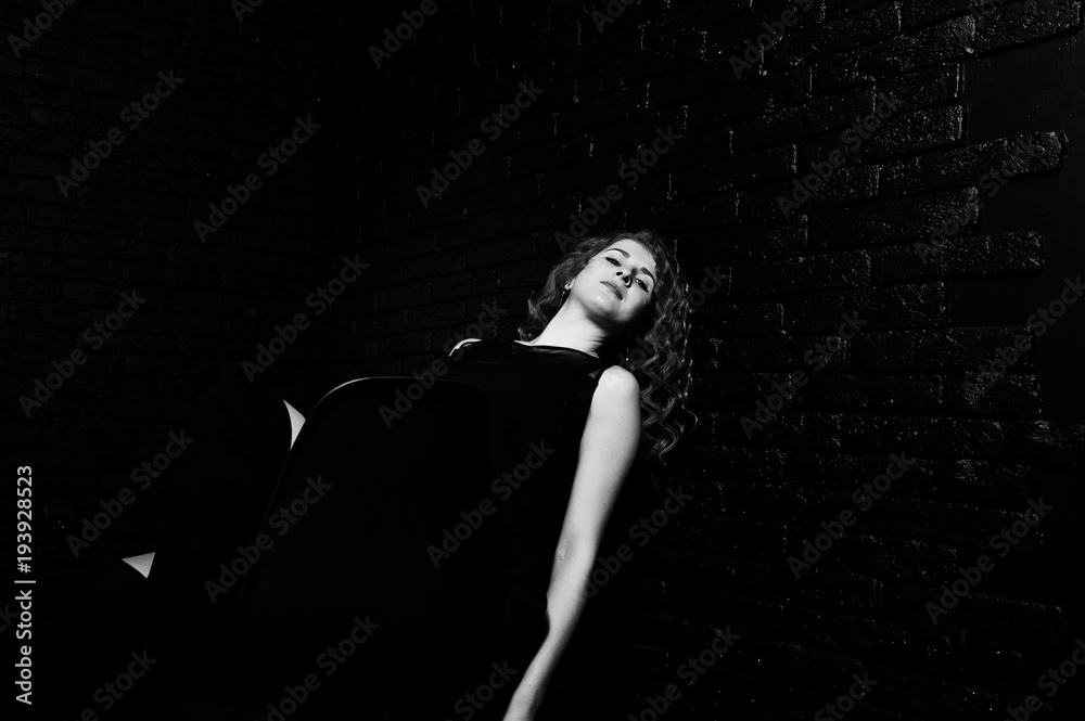 Curly hair girl at black clothes on studio against black brick wall. Curly hair girl at black clothes on studio against black brick wall.