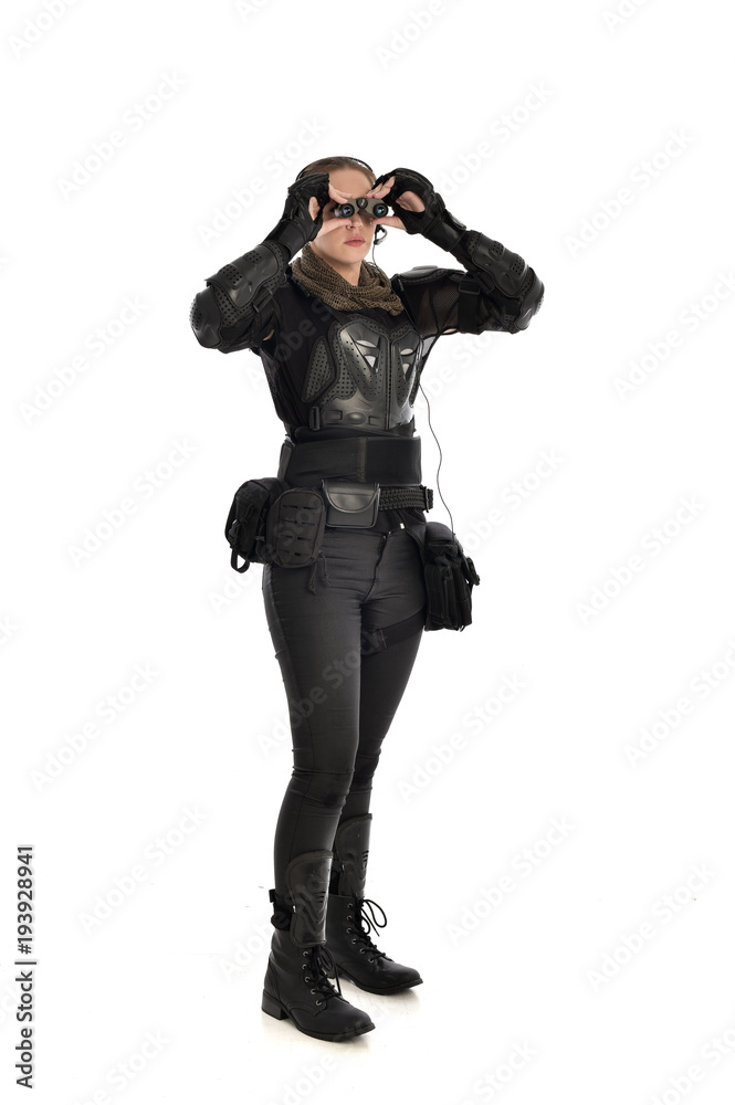 full length portrait of female soldier wearing black tactical armour holding a pair of binoculars, isolated on white studio background. full length portrait of female soldier wearing black tactical armour holding a pair of binoculars, isolated on white studio background.