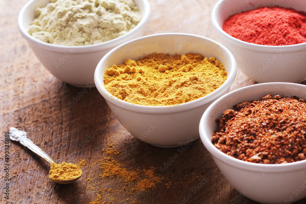 Various colorful spices on wooden table in bowls . Food and cuisine ingredients.