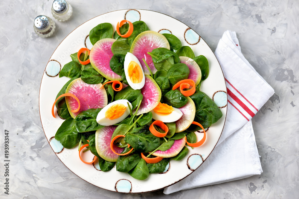 Healthy spinach baby salad, carrots, boiled egg and watermelon radish with olive oil, balsamic vinegar and soy sauce.
