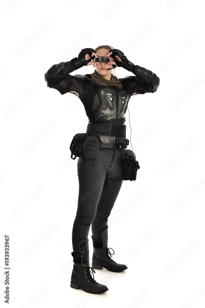 full length portrait of female soldier wearing black tactical armour holding a pair of binoculars, isolated on white studio background. full length portrait of female soldier wearing black tactical armour holding a pair of binoculars, isolated on white studio background.