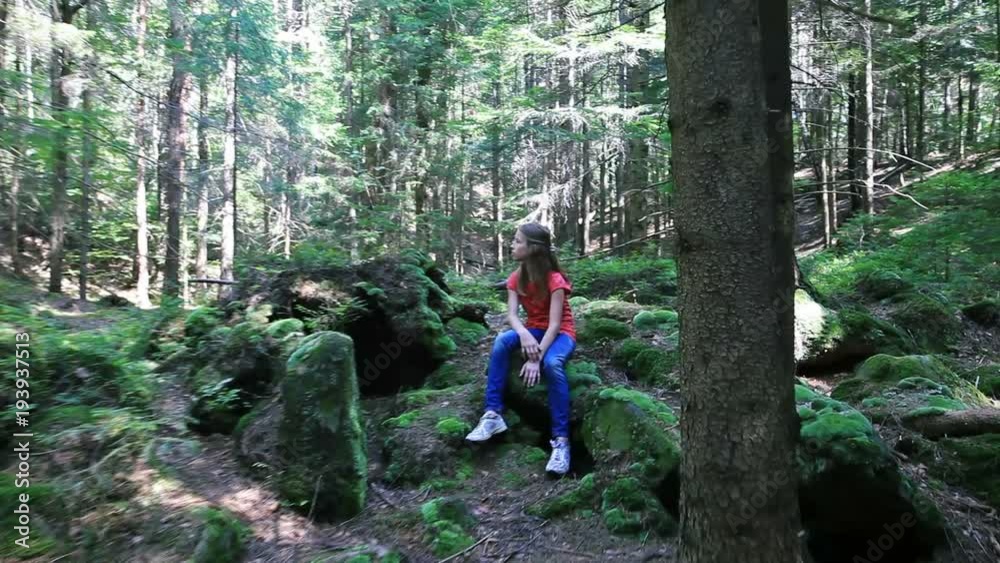 Teenage girl sitting on stone in forest Teenage girl sitting on stone in forest