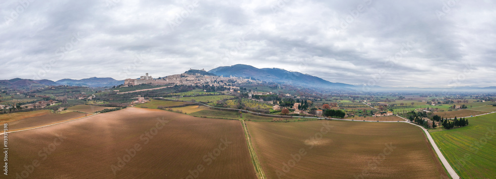 The view on Assisi, Umbria, Italy. Cloudy sky and cristmas smoke above. Flying nearby. Panorama 180