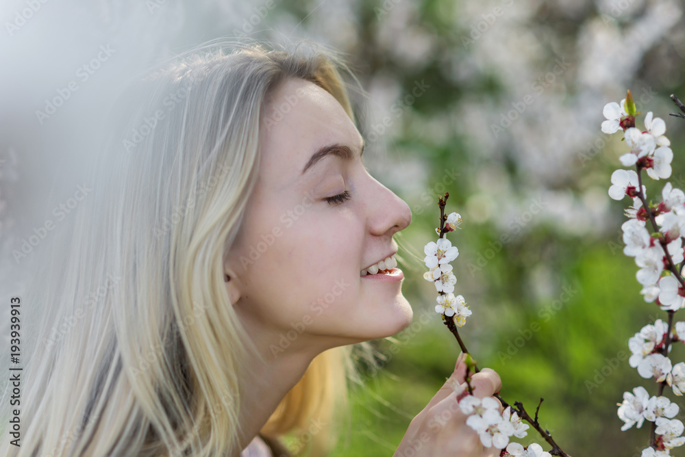 Closeup portrait of teenage girl inhales aroma of flowering apricot trees in the garden Closeup portrait of teenage girl inhales aroma of flowering apricot trees in the garden