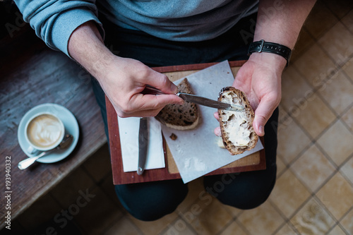 Mittelteil eines Mannes der Butter auf seinem Sauerteig Brot verteilt photo