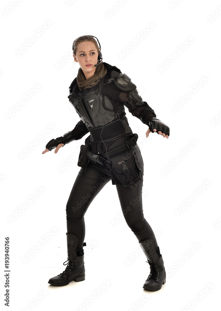 full length portrait of female  soldier wearing black  tactical armour, isolated on white studio background.