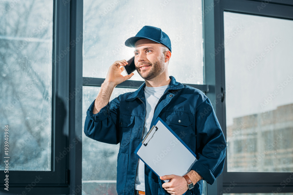 Courier holding clipboard and making a phone call Courier holding clipboard and making a phone call