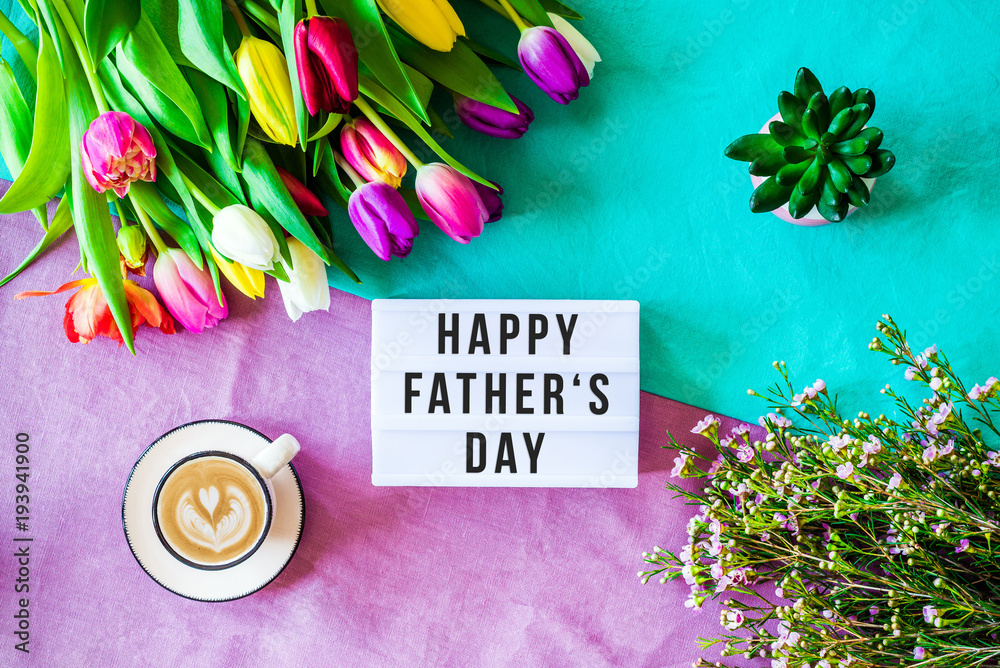 Fototapeta Happy father's day written in lightbox with spring flowers from above