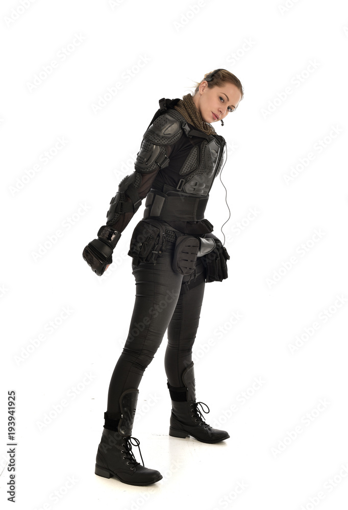 full length portrait of female  soldier wearing black  tactical armour, isolated on white studio background.