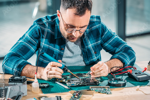 фотографія Hardware engineer in glasses soldering pc parts