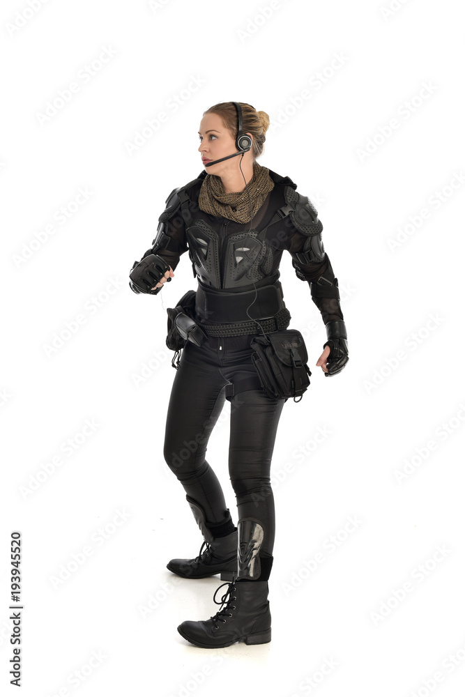 full length portrait of female  soldier wearing black  tactical armour, isolated on white studio background.
