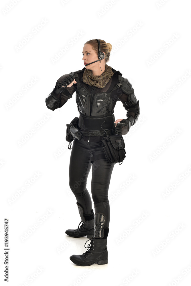 full length portrait of female  soldier wearing black  tactical armour, isolated on white studio background.