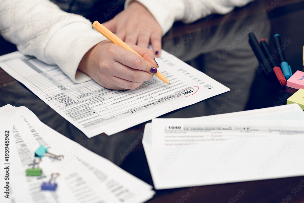 Fototapeta premium Woman fills the tax form, working with tax documents.Form 1040 Individual Income Tax return form. United States Tax forms 2017/2018.