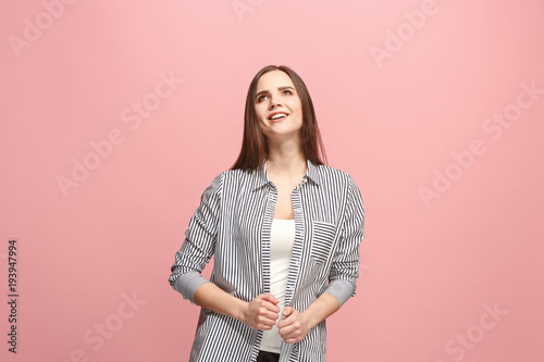 The happy business woman standing and smiling against pink background.