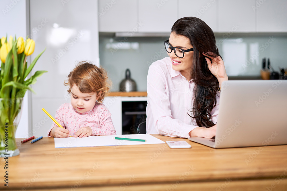 Mother working from home and taking care of her child Mother working from home and taking care of her child