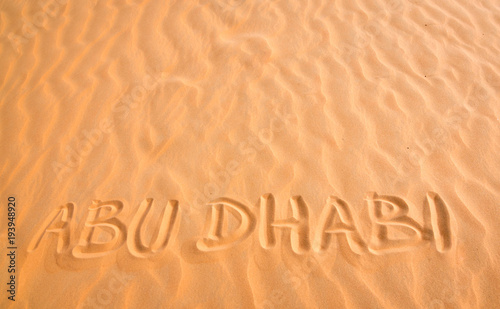Abu Dhabi handwritten text in desert sand.