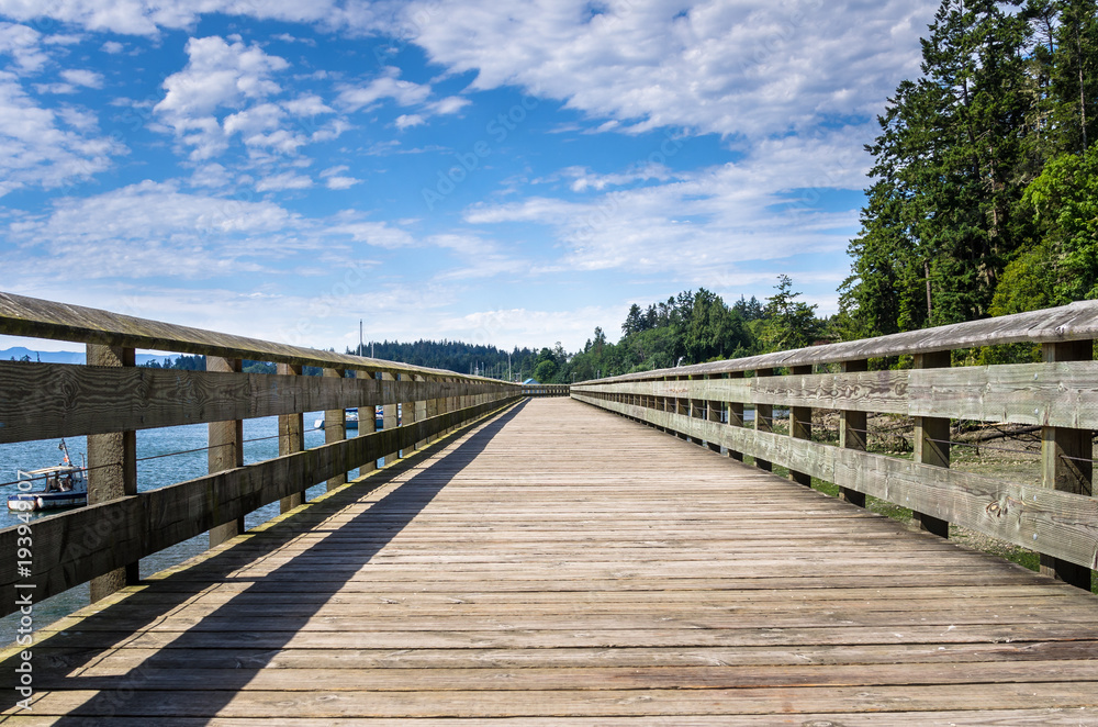 Empty Wooden Pier under Blue Sky with Clouds on a summer Morning. Sooke, BC, Canada.