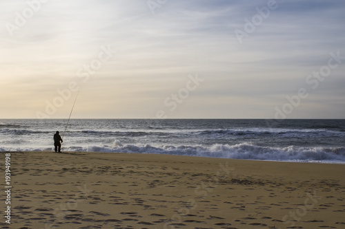 lonely fisherman on the shore of the stormy ocean