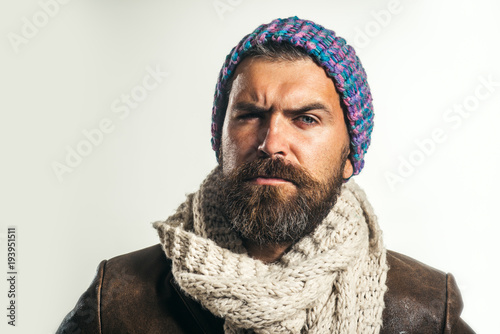Male fashion. Handsome man wearing demi-season clothing. Serious man with beard, brutal caucasian hipster in warm scarf wrapped around his neck, hat on head and jacket. Advertise autumn-winter fashion