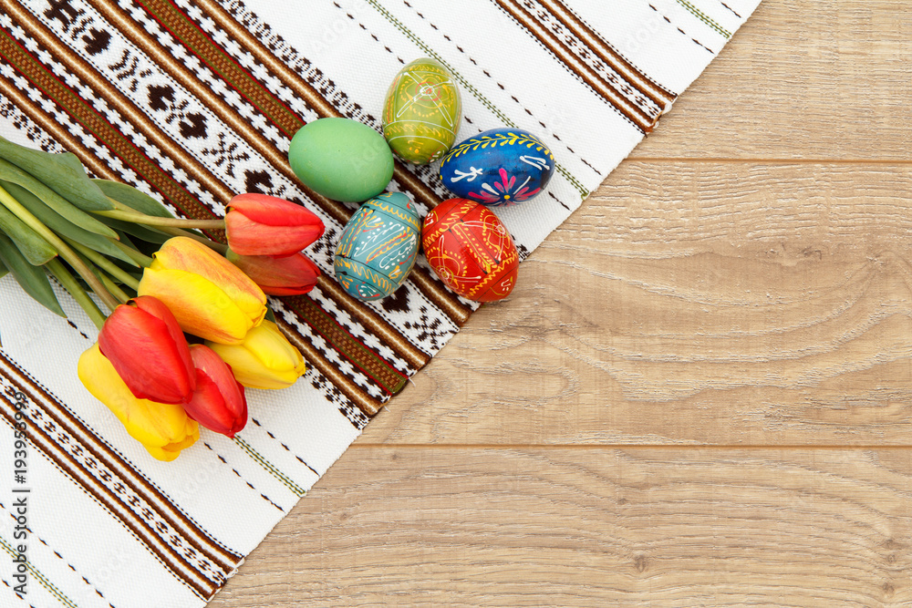 Painted Easter eggs, tulips and towel with ornament on wooden boards