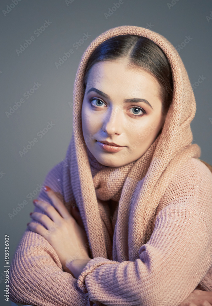 large emotional portrait of a beautiful girl in a knitted pink headscarf in the studio on a gray background. large emotional portrait of a beautiful girl in a knitted pink headscarf in the studio on a gray background.