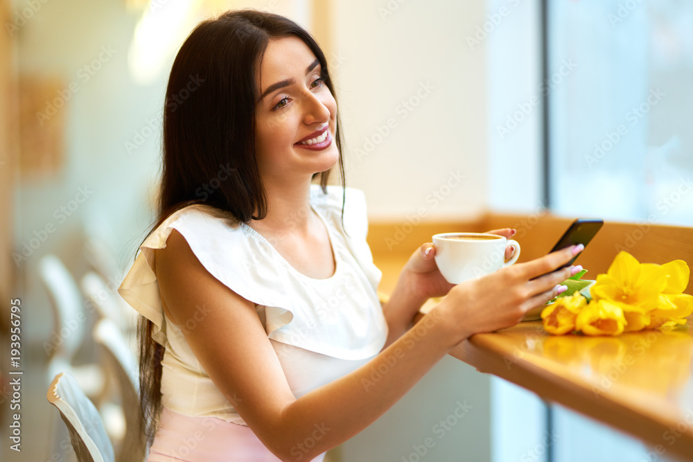 Beautiful Young Woman With Spring Tulips Flowers Bouquet At Cafe. Woman Drinking Coffee And Using Phone. Spring Style. Brunette Woman In Nice Spring.Beautiful Spring Mood. Fashion Spring/Summer. Beautiful Young Woman With Spring Tulips Flowers Bouquet At Cafe. Woman Drinking Coffee And Using Phone. Spring Style. Brunette Woman In Nice Spring.Beautiful Spring Mood. Fashion Spring/Summer.