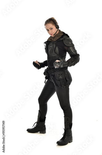 full length portrait of female soldier wearing black tactical armour, isolated on white studio background.