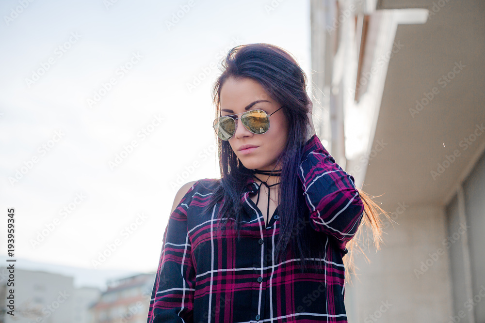 Stylish young brunette woman in sunglasses posing