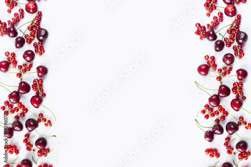 Ripe red currants and cherries. Berries at border of image with copy space for text. Background berries. Various fresh summer berries isolated on a white. Top view.