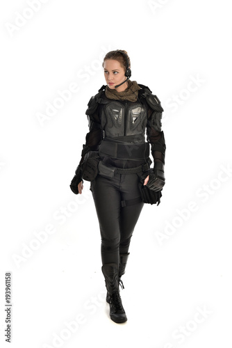 full length portrait of female  soldier wearing black  tactical armour, isolated on white studio background.
