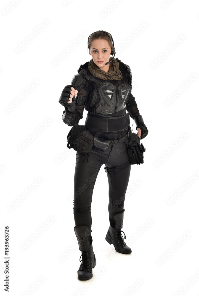 full length portrait of female  soldier wearing black  tactical armour, isolated on white studio background.