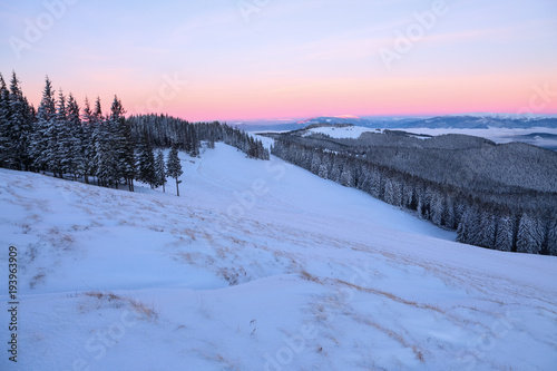 Landscape with high mountains covered with snow. Interesting frozen texture. Beautiful winter sunrise with orange and pink blue sky. Place for tourists. Christmas story.