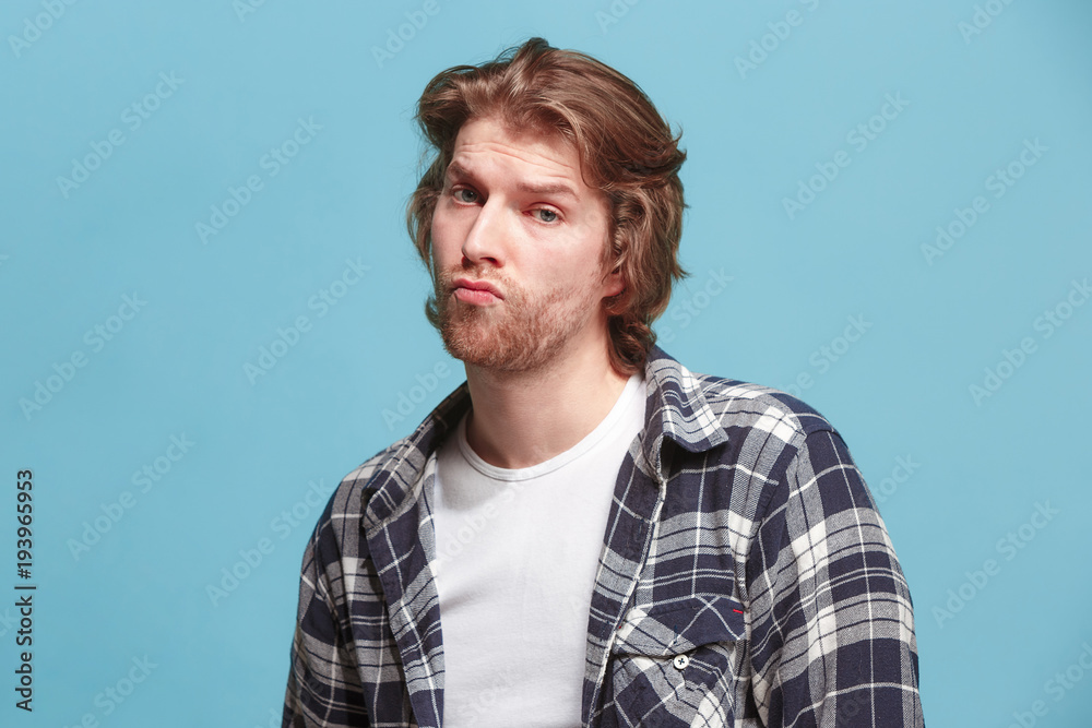 Let me think. Doubtful pensive man with thoughtful expression making choice against blue background Let me think. Doubtful pensive man with thoughtful expression making choice against blue background