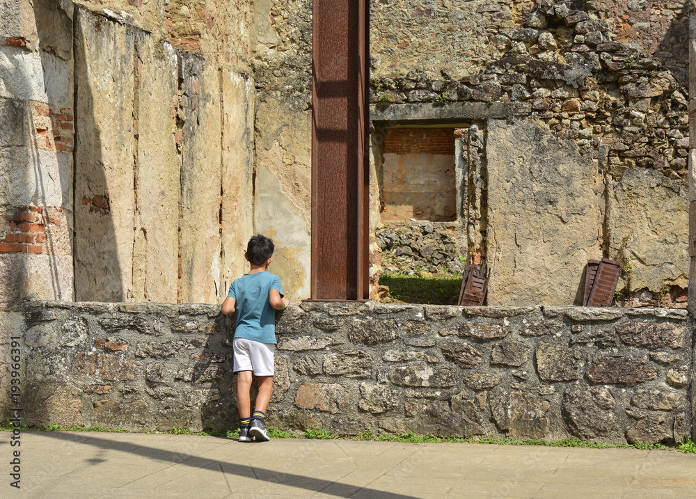 The boy looks at the ruined building during World War 2 in Oradour sur Glane France The boy looks at the ruined building during World War 2 in Oradour sur Glane France