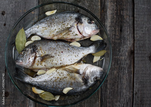 Dorado fish on a glass dish for baking, wooden background