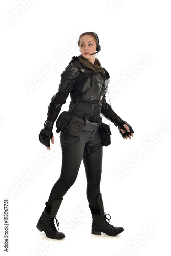 full length portrait of female soldier wearing black tactical armour, isolated on white studio background.