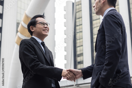 Successful negotiating business concept, Businessmen shaking hands after finishing meeting or setting goals and planning way to success in front of building .