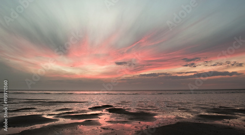 Sunset with pink clouds over Wenduine beach at low tide