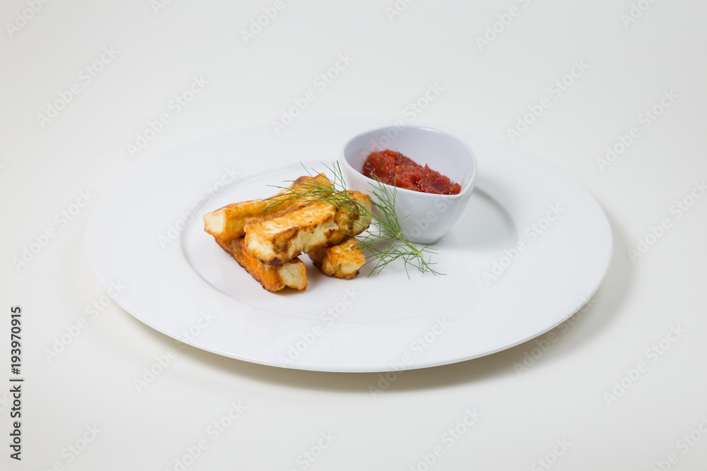 Fried halloumi and tomato dip on a white plate on a white background