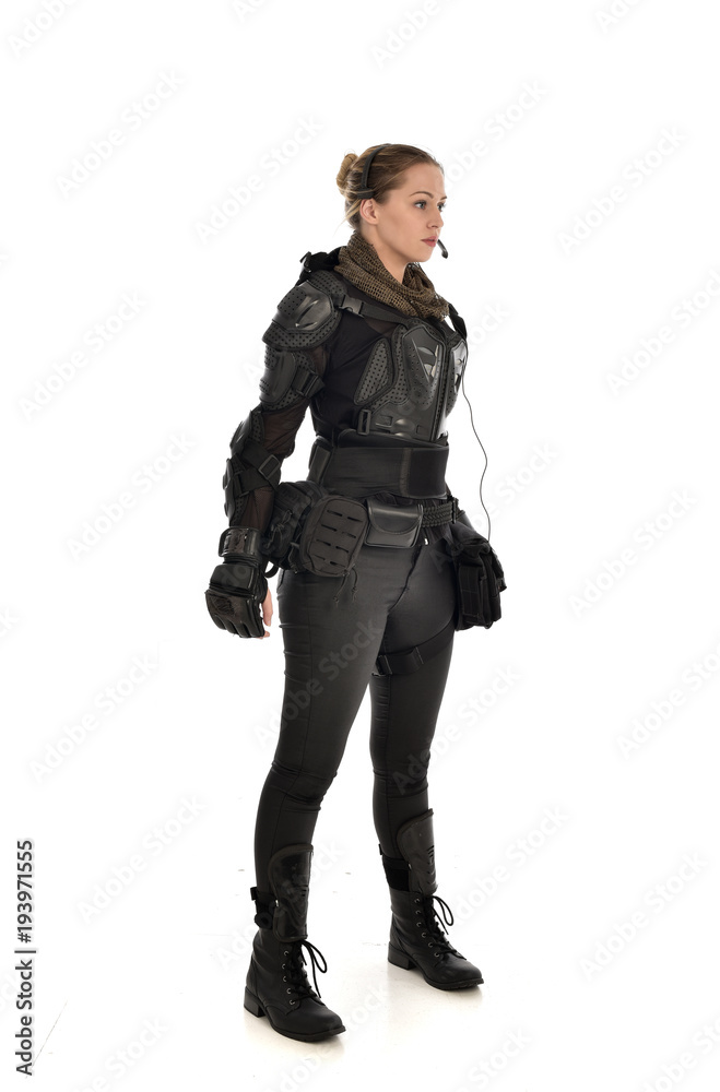 full length portrait of female  soldier wearing black  tactical armour, isolated on white studio background.